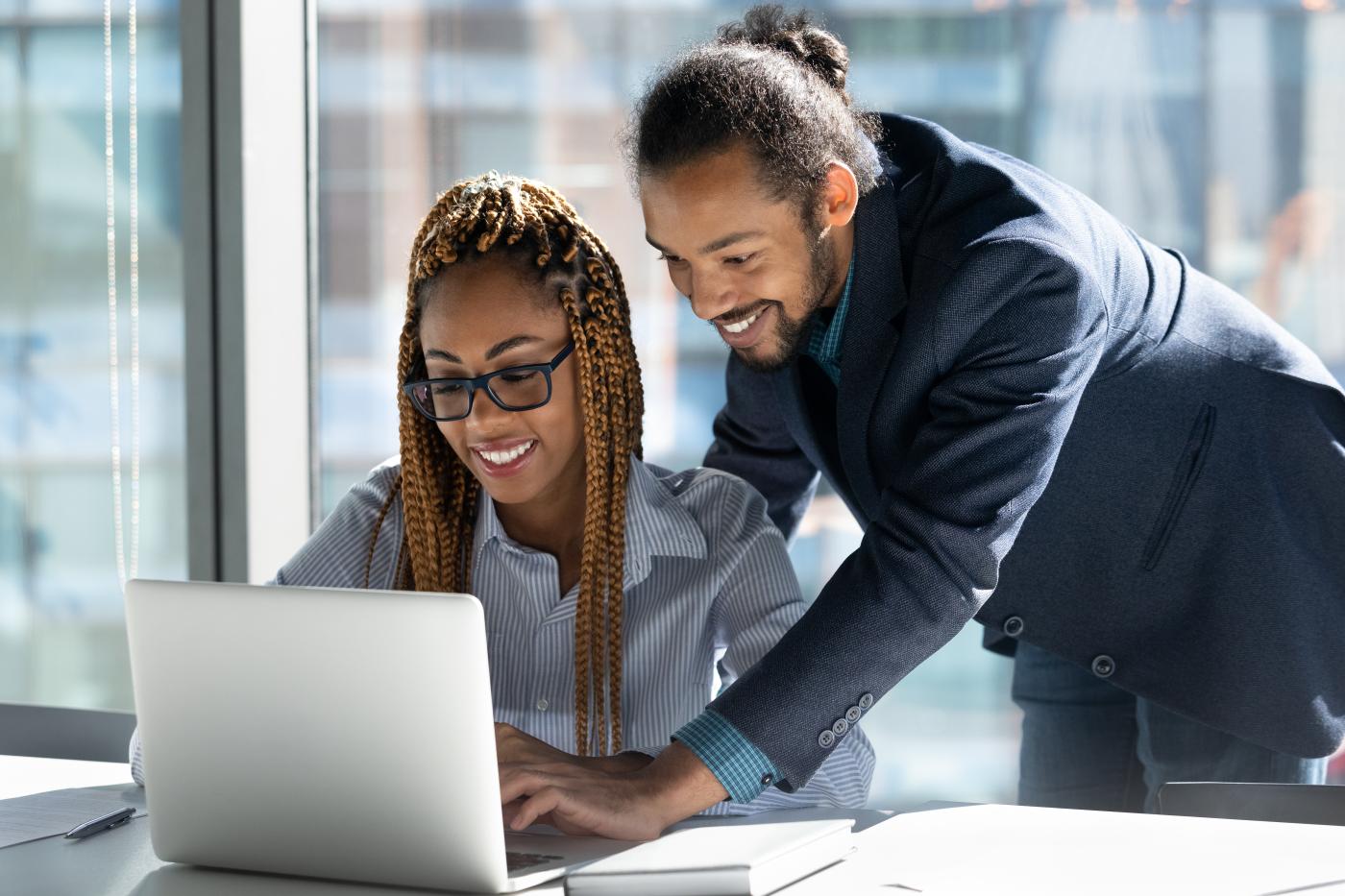 Two smiling people looking a computer together.