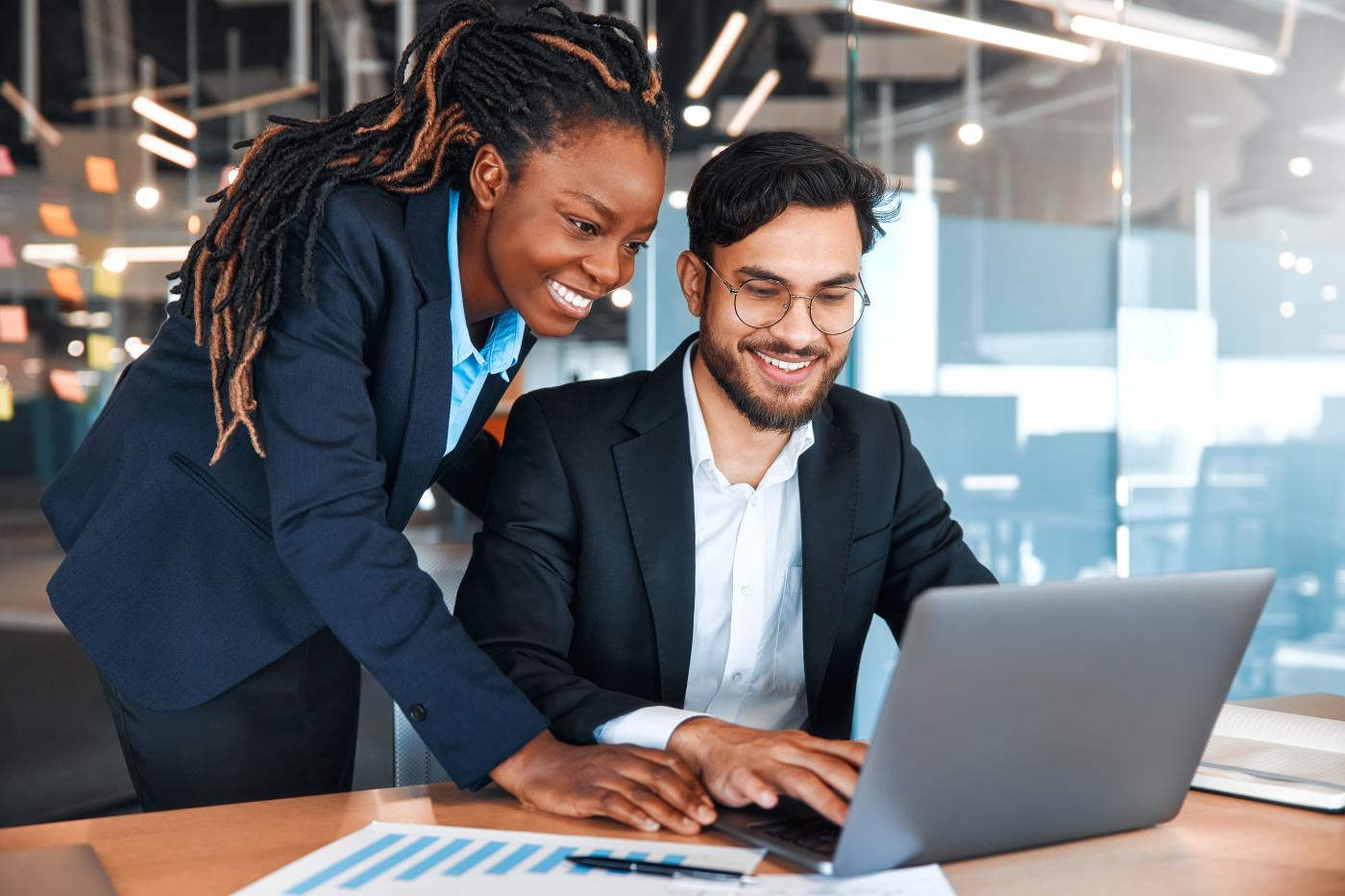 Two smiling people working on a computer.