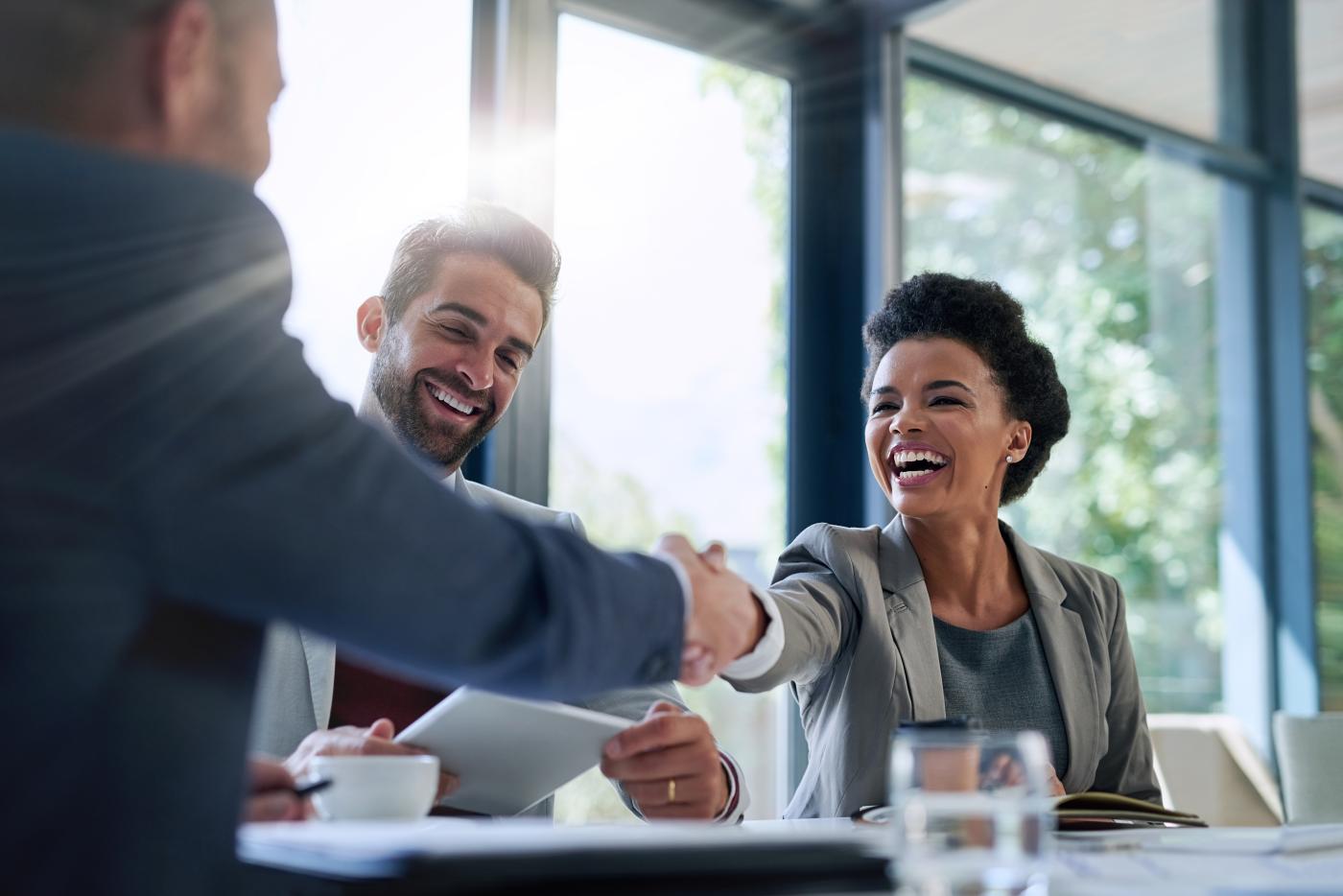 Two people shaking hands in a boardroom.